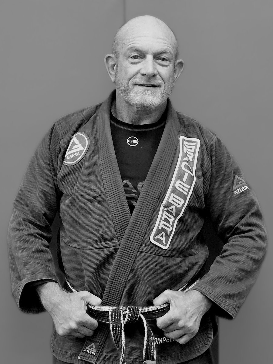 Professor John Montaldo, black belt instructor at Gracie Barra Seminole, standing in his gi in front of a plain gym wall